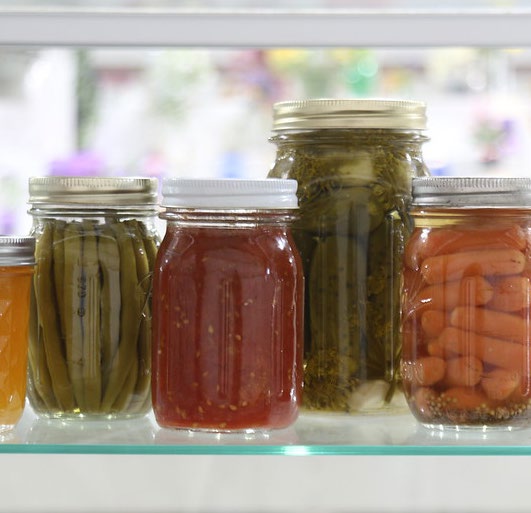 A group of vegetables that are in canning jars